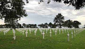 Military cemetery with white crosses arranged in rows.