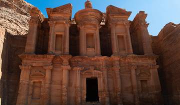 Ancient rock-carved facade in Petra under clear blue skies.