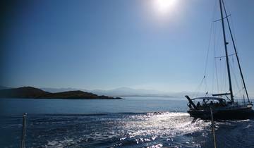 Sailboat cruising through calm waters with islands and mountains in the background.
