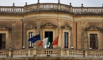 Historic building with three flags displayed.