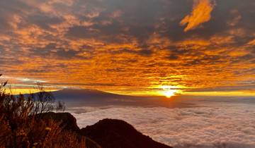 Spectacular sunrise with clouds and a silhouetted mountain.