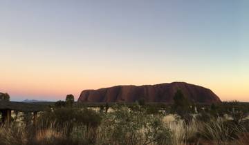 Uluru under a pastel-colored sky at dusk.