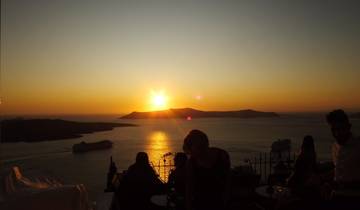 People enjoying a sunset over the ocean at a terrace.