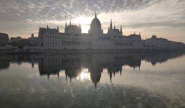 Stunning view of a grand building with a reflection in a river at sunset.