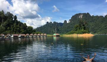 Scenic lake view with floating bungalows and mountains in the background.