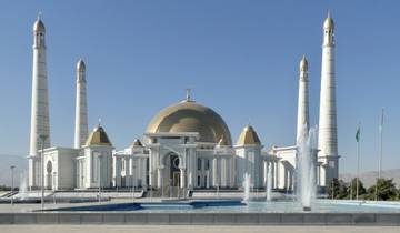 Majestic white and gold mosque with surrounding fountains.