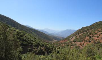 A scenic landscape view of lush green valleys and distant mountains under a clear blue sky.