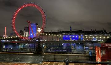 Night view of the London Eye and surrounding buildings lit up.