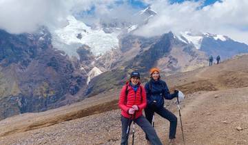 Two hikers posing with mountains and glaciers in the background.