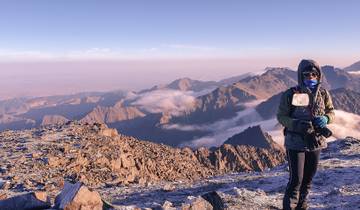 Person standing on a rocky mountain with vast views.
