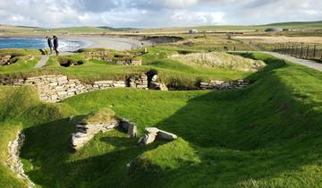 Grass-covered ruins by the sea with visitors