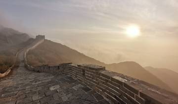 Misty view of a stone wall extending over hills with morning sun.