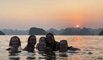 Group of women swimming with scenic karst landscape at sunset.