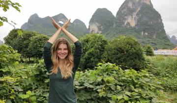 Person posing in front of karst mountains in a lush green setting.