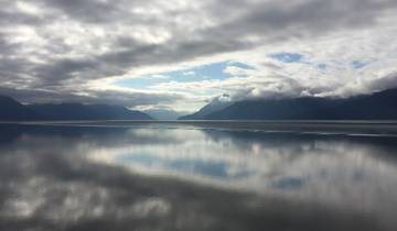 Serene view of a fjord with mountains and reflection in the water.