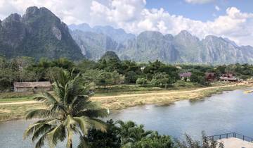 Breathtaking landscape of a river, palm trees, and towering peaks.