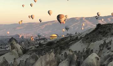 Hot air balloons over the Cappadocia landscape at sunrise.