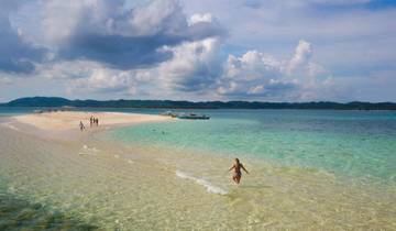People enjoying a sandbar with turquoise water around it.