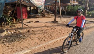Woman cycling along a rural roadside scene.