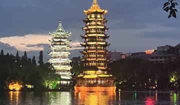 Two illuminated pagodas reflected in a body of water at dusk.