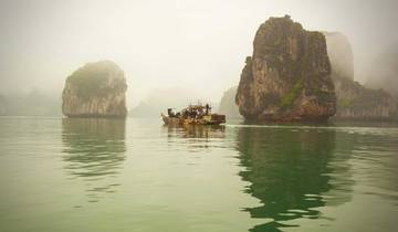 Misty bay with rock formations and a boat.