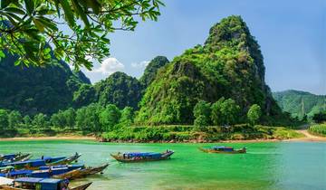 Scenic river with boats and a large grassy hill.