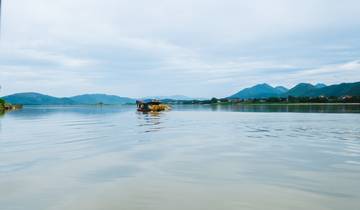 Scenic view of a boat on a calm lake with distant mountains.