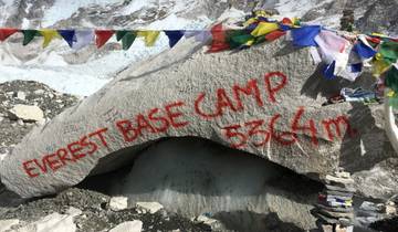Rock with 'Everest Base Camp' inscription surrounded by colorful flags.