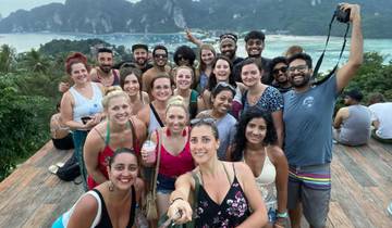 Large group selfie with a scenic ocean view in the background.