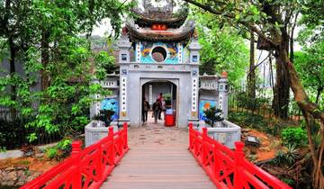 Entrance to Ngoc Son Temple with a red bridge and greenery.