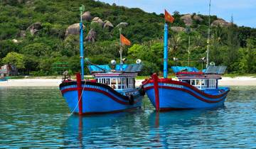 Two blue fishing boats with flags in crystal clear water.
