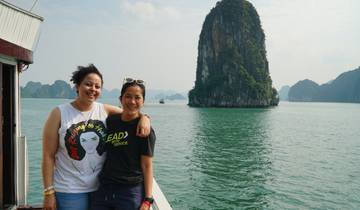 Two people smiling on a boat with limestone karsts in the background.