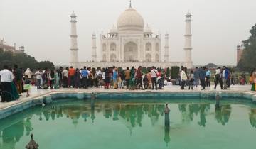 Crowds visiting the Taj Mahal with a reflecting pool in the foreground.