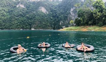Four people floating on water with inner tubes in a scenic lake.