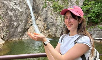 A woman posing with a waterfall in the background.