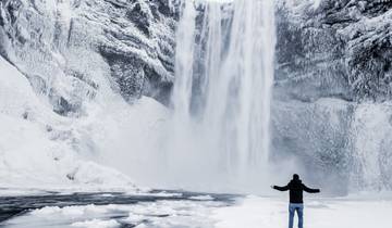 Person standing in front of a large snowy waterfall.