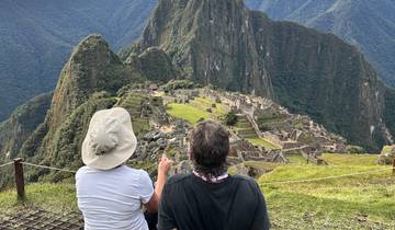 People sitting with a view of the archaeological site at Machu Picchu.