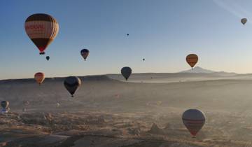 Hot air balloons over a scenic landscape at sunrise.