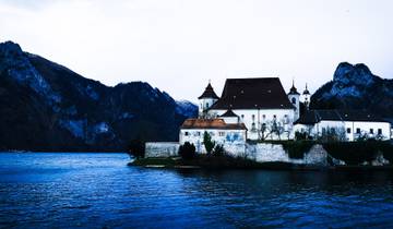 A castle near a lake with mountains.