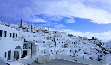 Panoramic view of white buildings on a hillside under a blue sky.