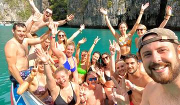 A group of people on a boat in a turquoise blue sea surrounded by cliffs