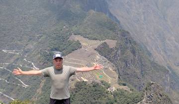 A person with arms outstretched, overlooking a mountain vista.