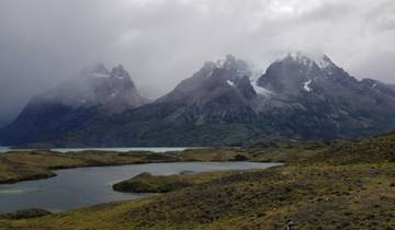 A scenic view of mountains shrouded in clouds with a lake.