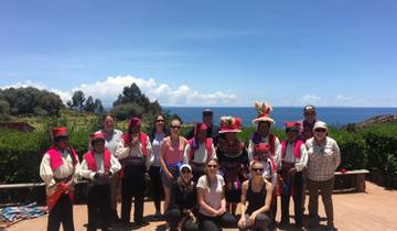 Group with locals in vibrant attire by a lake.