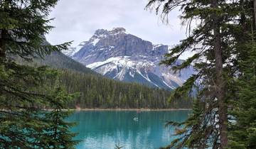 Serene lake surrounded by forest and mountain peaks.