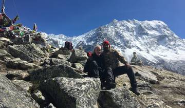 Two people sitting on rocks in a snowy mountain setting.