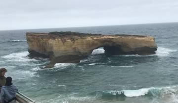 A rock formation in the ocean with people observing.