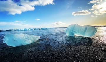 Icebergs on a black sand beach with a bright sky.