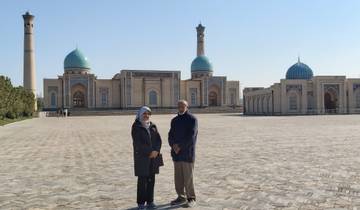 Two people standing in front of a historical building with large domes.