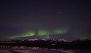 Vibrant Northern Lights over snowy mountains.